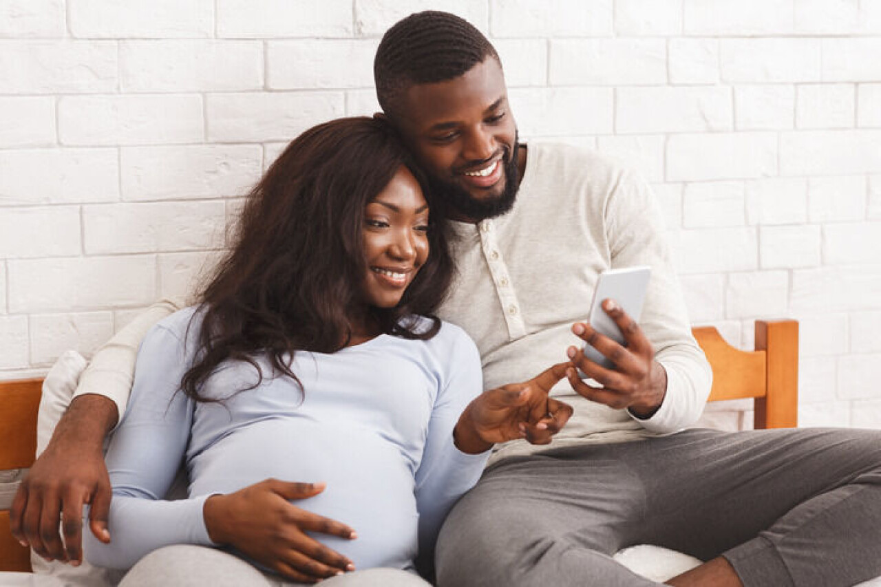 Gravid kvinna och man kollar på en mobiltelefon